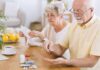 Everyday Pill That Quietly Primes A Heart Attack Older man taking pills at a table while woman reads instructions