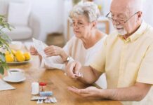 Everyday Pill That Quietly Primes A Heart Attack Older man taking pills at a table while woman reads instructions