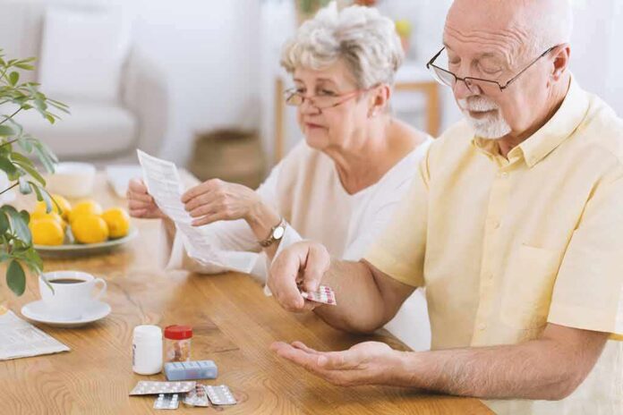 shutterstock_1011163015 Older man taking pills at a table while woman reads instructions