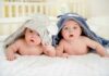 two babies under hooded towels on a bed
