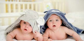 two babies under hooded towels on a bed