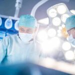 Surgeons in operating room under bright surgical lights