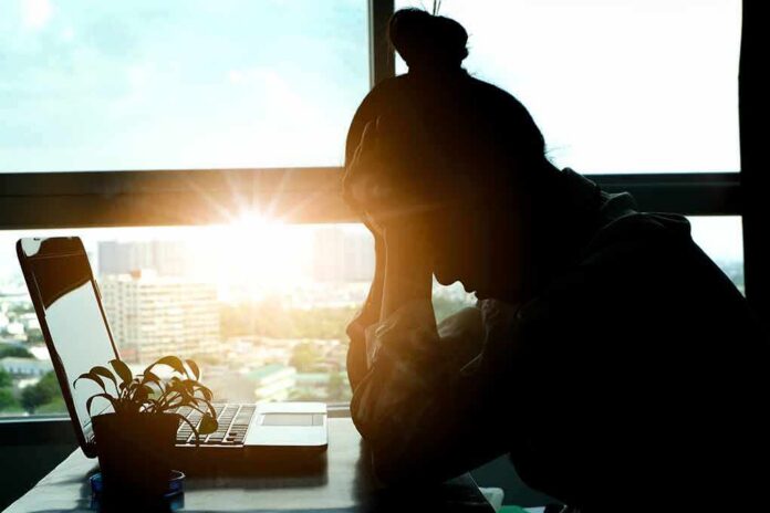 silhouetted person at a desk with head in hands