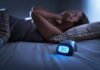 Body Clock Rhythm and Dementia Risk Person lying awake in bed beside a glowing digital alarm clock