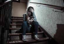 teen girl sitting on stairs looking at phone with hand on forehead