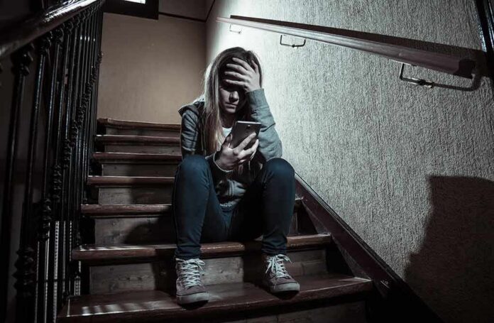 teen girl sitting on stairs looking at phone with hand on forehead