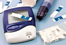 Blood glucose monitor with testing strips and a lancing device on a blue background