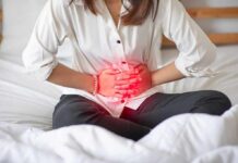 The Constipation Line You Mustn’t Cross Woman holding her abdomen in pain while sitting on a bed