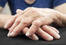 Elderly hands resting and crossed on a dark surface