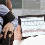 Technician reviews polygraph readings on a tablet beside a seated subject