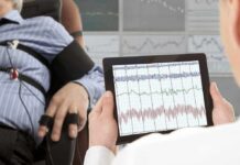 Technician reviews polygraph readings on a tablet beside a seated subject