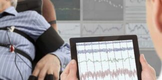 Technician reviews polygraph readings on a tablet beside a seated subject