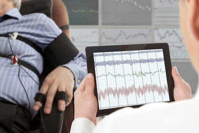 shutterstock_327795071 Technician reviews polygraph readings on a tablet beside a seated subject