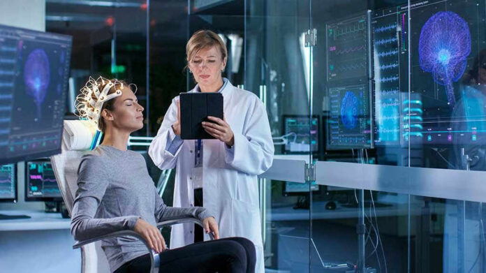 Patient wearing EEG cap sits while clinician reviews data on tablet