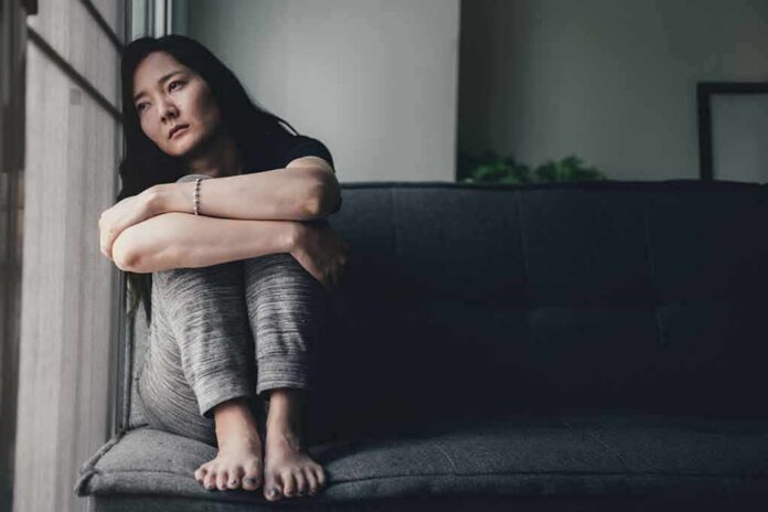 1783889883141-osv14b-shutterstock-1360242140 Woman sitting on a couch hugging her knees by a window