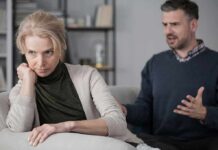 Upset woman sitting on couch while man gestures behind her