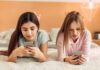 Scroll Trap Linked To Memory Slide Two girls lying on a bed using smartphones