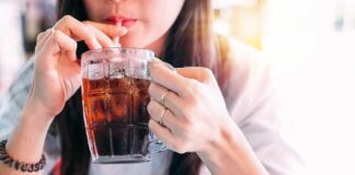 person sipping iced drink from a glass mug with a straw