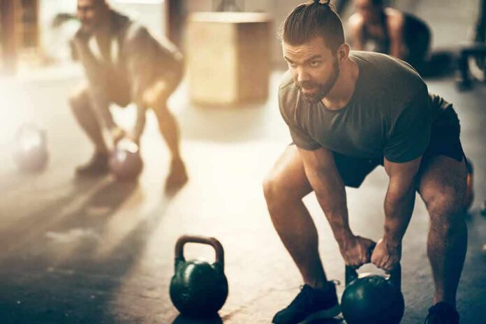 shutterstock_1043370892 Man lifting kettlebell in gym