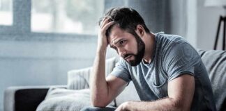Man sitting on a couch with head in hand