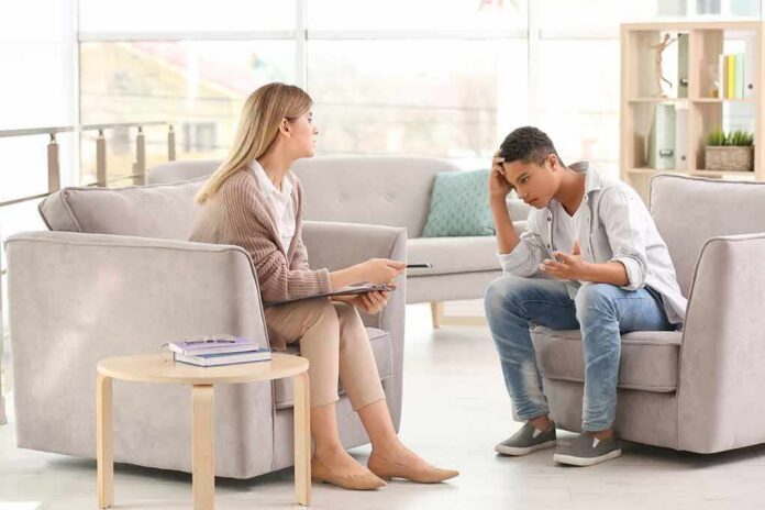 shutterstock_1080190124 Teen talking with therapist in a bright office