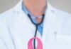 Silent Crisis: Millions Miss Cancer Checks Doctor holding stethoscope with pink ribbon in front