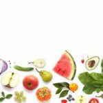 Assorted fresh fruits and vegetables arranged along the bottom on white