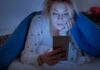 The 20-minute rule for insomnia, finally explained by neuroscientists Woman under a blanket looking at a smartphone in bed