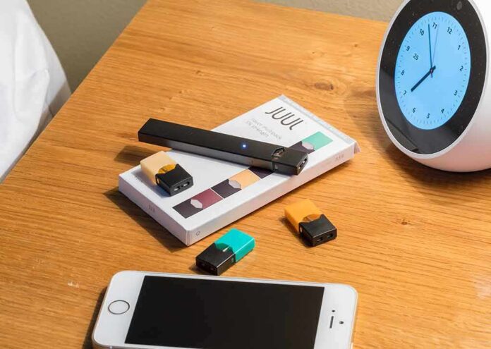 vape pen and pods on a wooden nightstand