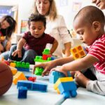 Karyn Polito with toddlers building blocks on a play mat