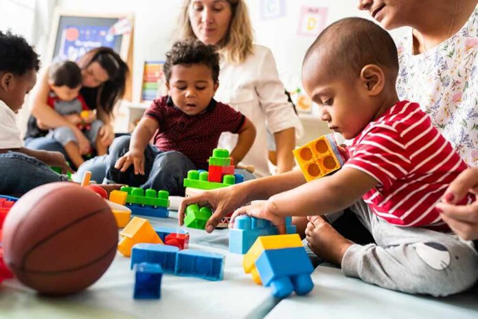 shutterstock_1247691913 Karyn Polito with toddlers building blocks on a play mat