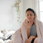 Woman wrapped in blanket touching her throat