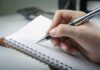 Adult ADHD and Perfectionism: The Surprising Link A hand holding a pen above a blank notebook page