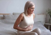 Chronic Pain Management – A Patient’s Guide Older woman sitting on bed holding her stomach in pain