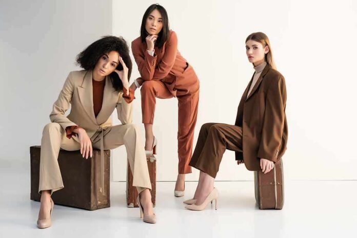 Three women in tailored suits posing on vintage suitcases