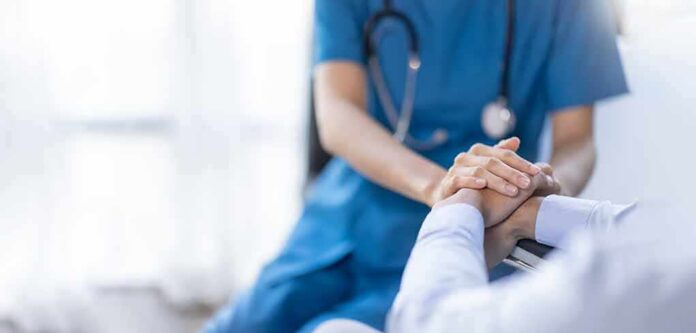 shutterstock_2219183715 Nurse comforting a patient by holding hands