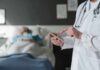 Heart Inflammation Surge Stuns Doctors Doctor using tablet beside hospital patient