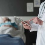 Doctor using tablet beside hospital patient