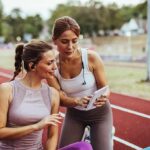 Two women at a running track looking at a tablet