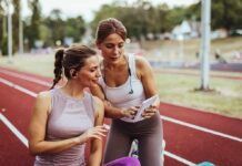 Two women at a running track looking at a tablet