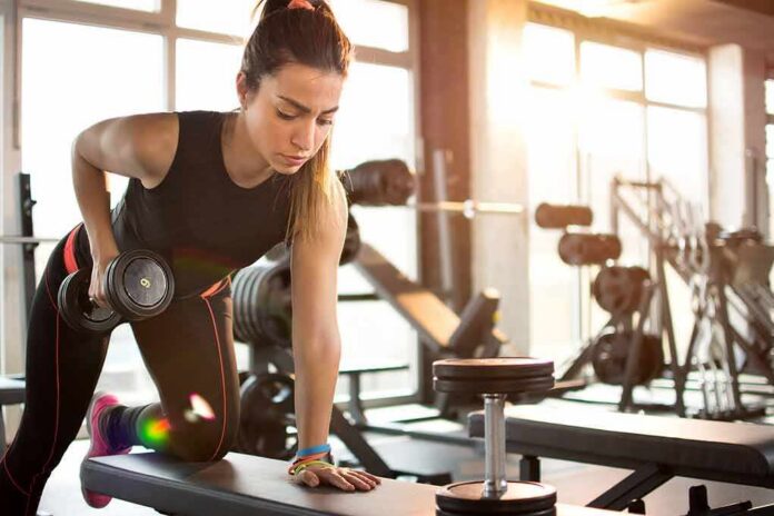 Woman performing dumbbell row in a gym