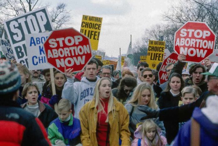 shutterstock_620193926 Protesters holding signs at an anti-abortion march
