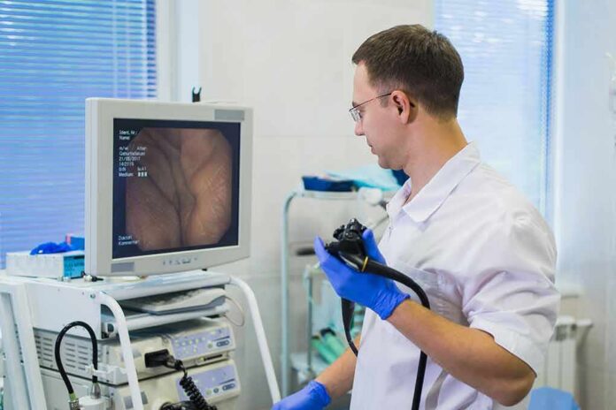 Doctor holding endoscope beside monitor during procedure