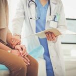 Doctor comforting patient while reviewing medical chart
