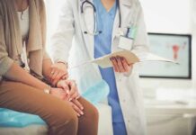 The Urination Habit That Could Be Wrecking Your Bladder Doctor comforting patient while reviewing medical chart