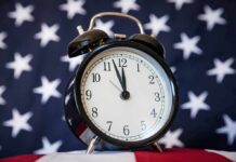 Black alarm clock in front of a star-spangled flag
