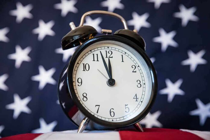shutterstock_1005673171 Black alarm clock in front of a star-spangled flag