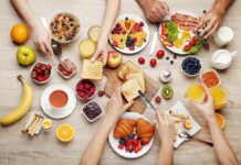 Breakfast table with assorted foods and hands serving
