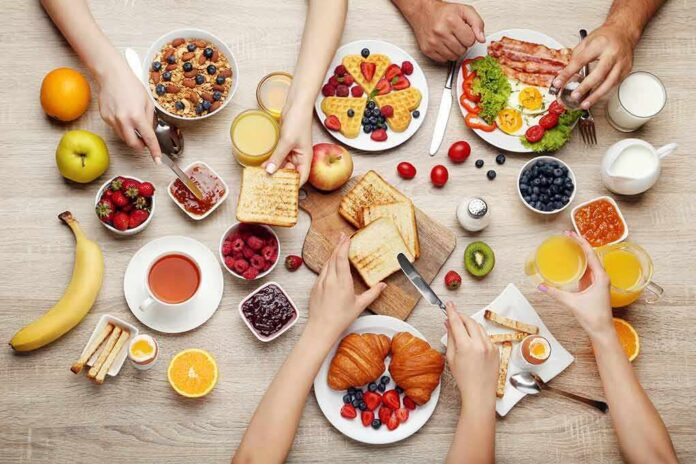 Breakfast table with assorted foods and hands serving