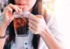 WHO Throws Cold Water On Diet Drinks person sipping iced drink from a glass mug with a straw